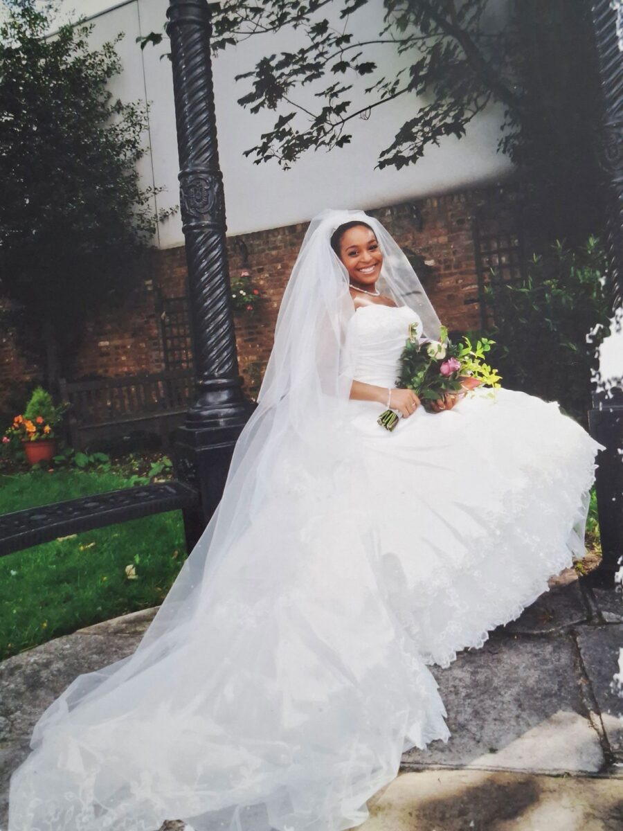 Tania in her strapless Sophia Tolli lace gown with a cathedral veil, smiling and holding a floral bouquet at her autumn wedding.