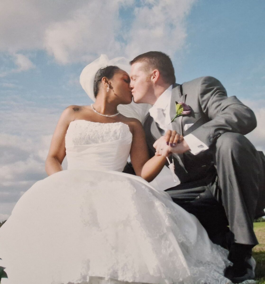 Tania in her strapless Sophia Tolli lace gown sharing a kiss with James beneath a bright autumn sky at their Blackheath wedding.