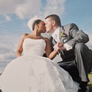 Tania in her strapless Sophia Tolli lace gown sharing a kiss with James beneath a bright autumn sky at their Blackheath wedding.
