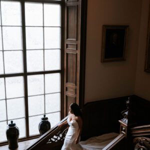 Sophie in her Maggie Sottero strapless mermaid gown pausing on the grand staircase at Cluny Castle, Aberdeen, her train trailing behind her.