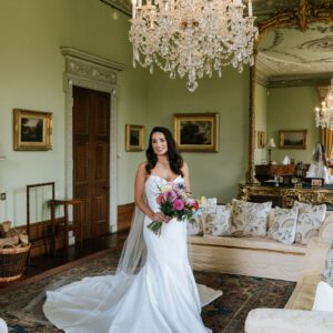 Sophie in her strapless Maggie Sottero mermaid gown holding a colourful bouquet inside the grand drawing room at Cluny Castle, Aberdeen.