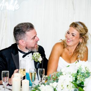 Sarah in her strapless corset Mori Lee gown laughing with Anthony at the top table during their wedding reception at The Manor at Bickley.