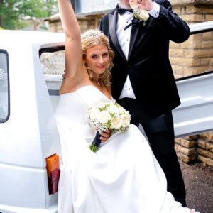 Sarah in her strapless Mori Lee corset gown raising a glass of prosecco beside Anthony, next to the prosecco van at The Manor at Bickley.