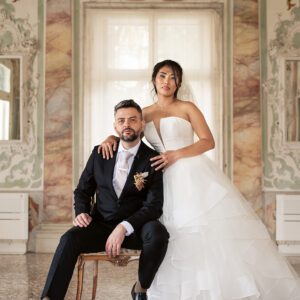 Bella in her strapless Justin Alexander tiered waterfall gown beside Alessandro in a frescoed hall at Palazzo Sturm, Bassano del Grappa.